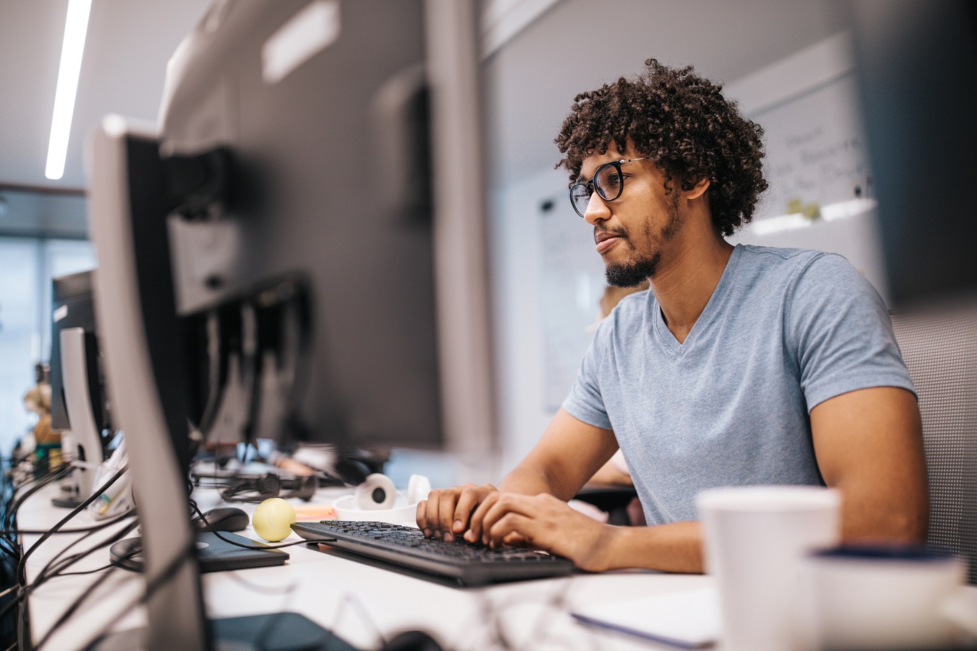 Young African American programmer working on desktop PC in the office.